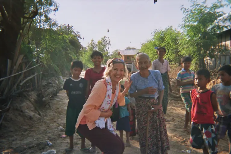 Image montrant Melisdjane entouré d'enfants et personnes d'un village, tout le monde est souriant